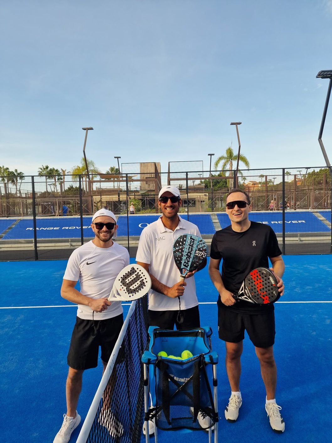 Three players with their rackets at the end of a session
